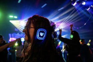 Guest dancing in glowing blue-channel silent disco headphones