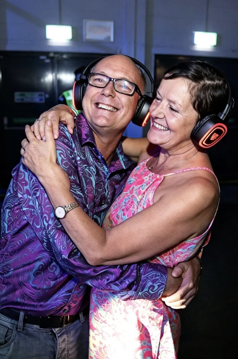 Couple hugging and laughing in silent disco headphones