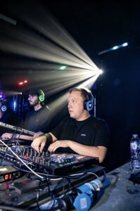 DJ mixing at the silent disco booth under a white light beam