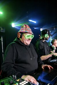 DJ in a bucket hat and LED glasses playing a silent disco