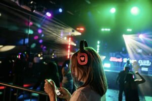 Guest in red-channel glowing headphones watching the booth