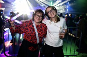 Two guests smiling with glow sticks at a silent disco