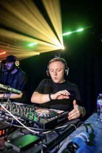 DJ at the decks under yellow light beams