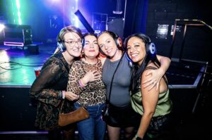 Four friends hugging in silent disco headphones