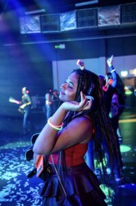 Guest dancing with a hand on her headphones under blue light