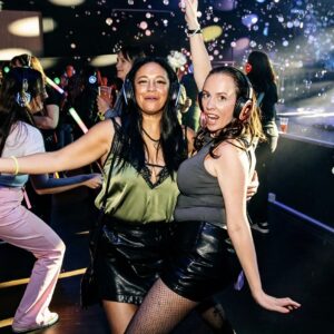 Two friends dancing among bubbles at a silent disco