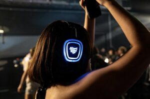 Guest with arms up in glowing blue silent disco headphones