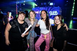 Four friends with foam light sticks in front of the booth
