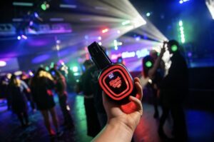 Glowing red-channel headphones held up over the dance floor