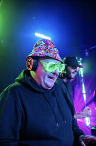 DJ in a bucket hat and LED glasses under green light