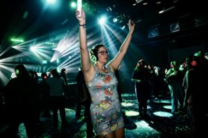 Guest dancing with arms up under green lights