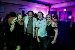 Group of four friends in headphones under purple light