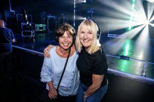 Two friends smiling in headphones by the stage