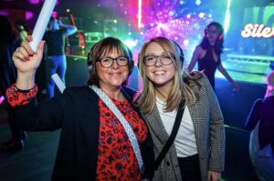 Two guests with a foam light stick under colourful lights