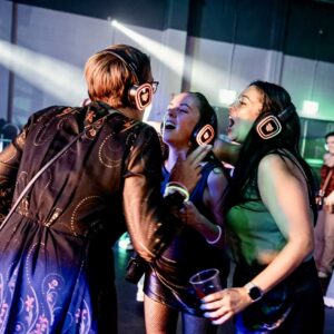 Friends singing along in glowing orange headphones