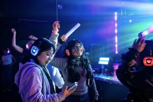 Friends dancing with foam light sticks under blue light
